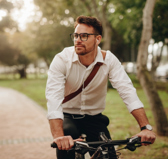 Mann mit Brille auf Fahrrad im Park.